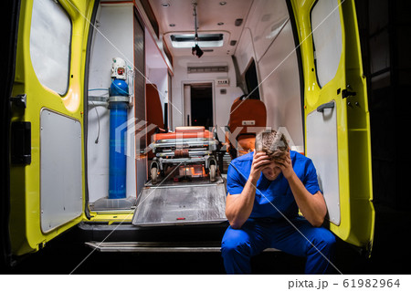 Confused corpsman in blue uniform sit on the ambulance car 61982964