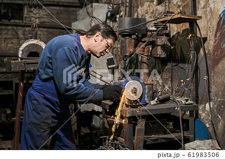 handicraftsman processes a blacksmith's tool on a 61983506