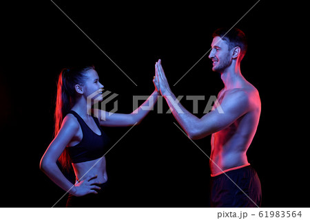 Young successful sportsman and sportswoman giving each other high five Young successful sportsman and sportswoman giving each other high five 61983564