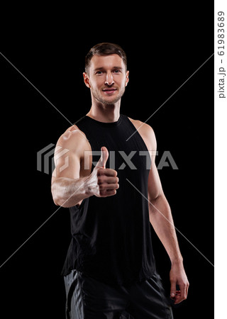 Happy young successful muscular athlete showing thumb up in isolation 61983689