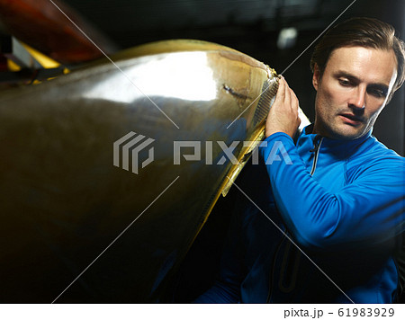Young concentrated Caucasian sportsman in blue swimming jacket carrying boat Young concentrated Caucasian sportsman in blue swimming jacket carrying boat 61983929