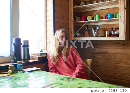 Portrait of a pensive woman sitting at window 61984130