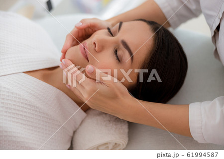 Masseuse massaging lady face at beauty salon Masseuse massaging lady face at beauty salon 61994587