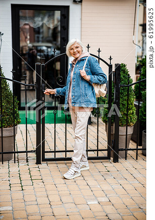 Happy elderly female at gate to house stock photo 61995625