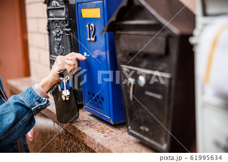 Woman opening mailbox in street stock photo Woman opening mailbox in street stock photo 61995634