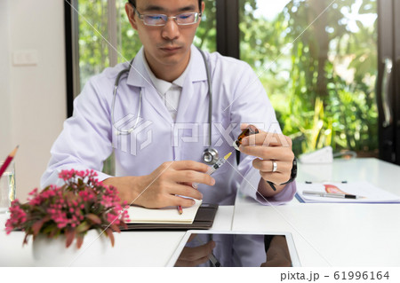 Doctor holding injection needle and vaccine bottle 61996164