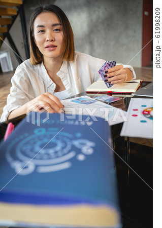 Calm woman is analysing her horoscope indoors Calm woman is analysing her horoscope indoors 61998209