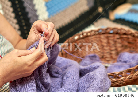 Woman is knitting a blue warm sweater. An aged 61998946
