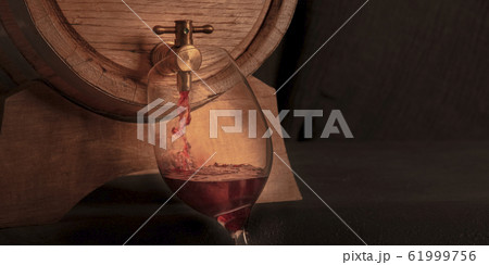 Pouring wine into a glass from an oak barrel, a toned panorama on a dark background with copy space Pouring wine into a glass from an oak barrel, a toned panorama on a dark background with copy space 61999756