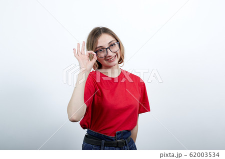 Lady having nice glasses, keeping fingers on it, showing three fingers, smiling Lady having nice glasses, keeping fingers on it, showing three fingers, smiling 62003534