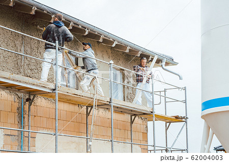 Plasterer standing on scaffolding at construction site 62004003
