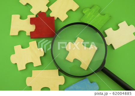 Jigsaw puzzle pieces with magnifying glass 62004885