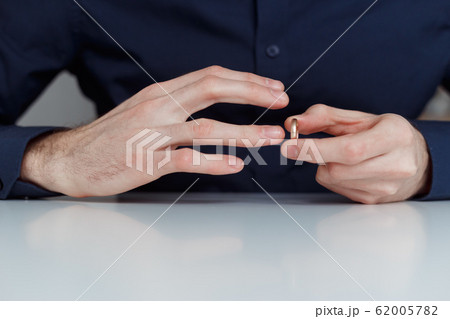 Young man is taking off the wedding ring. Close up view. Divorce concept 62005782