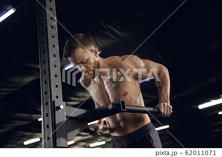 Young healthy male athlete doing exercises in the gym Young healthy male athlete doing exercises in the gym 62011071