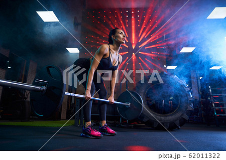 Woman doing deadlift with barbell in gym. 62011322