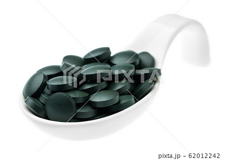 Vitamin and mineral supplements for vegetarians spirulina in tablets in a ceramic spoon, close-up. Vitamin and mineral supplements for vegetarians spirulina in tablets in a ceramic spoon, close-up. 62012242