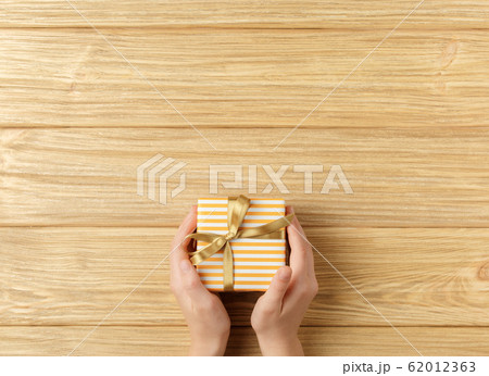 gift box in the hands on a wooden background gift box in the hands on a wooden background 62012363
