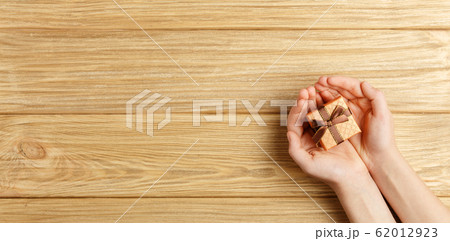 gift box in the hands on a wooden background gift box in the hands on a wooden background 62012923