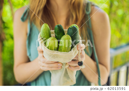 Cucumbers in a reusable bag in the hands of a young woman. Zero waste concept 62013591