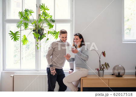 Businesspeople with tablet standing indoors in office, working. 62017518