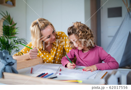 A cute small girl with mother indoors at home, drawing pictures. A cute small girl with mother indoors at home, drawing pictures. 62017556