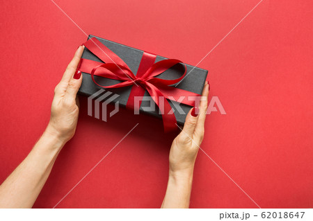 Woman's hands holding black gift box with bow 62018647