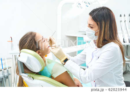 Girl sitting at dental chair with open mouth during oral check up while doctor. Visiting dentist office. Dentistry concept. 62023944
