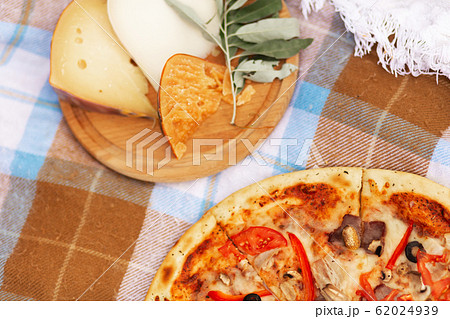 Pizza and cheese platter on a checkered bedspread. 62024939