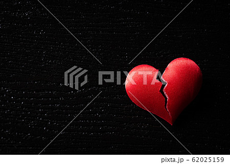 Broken red heart on black wooden background. Broken red heart on black wooden background. 62025159