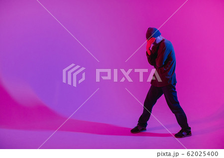 Young Man in a Jumper Dancing Contemporary Dance in Studio. Breakdancing. Dance School Poster. Copy Space. Battle competition announcement. Pink and Blue Background. 62025400