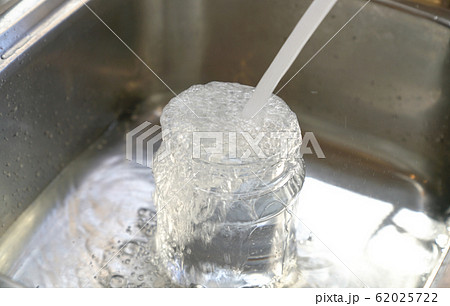 Water from tap into plastic container and overflow 62025722