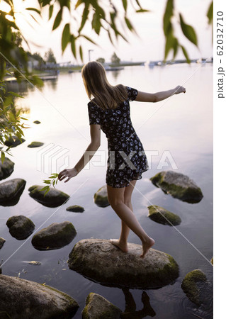 Woman balancing on rock in sea 62032710