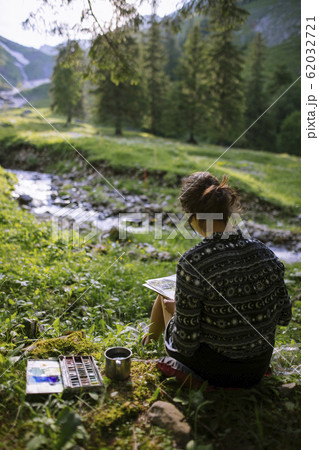 Woman painting with watercolors by river in Appenzell, Switzerland Woman painting with watercolors by river in Appenzell, Switzerland 62032721