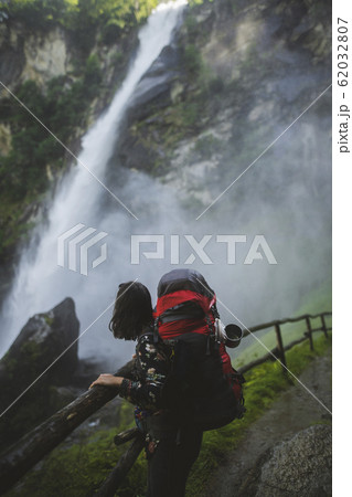 Woman wearing backpack by waterfall 62032807