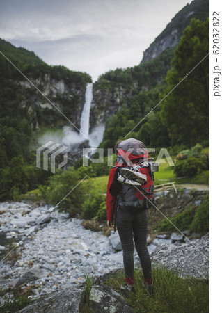 Woman wearing backpack with waterfall in distance 62032822