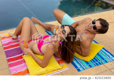 Happy young couple relaxing near the swimming pool 62033800