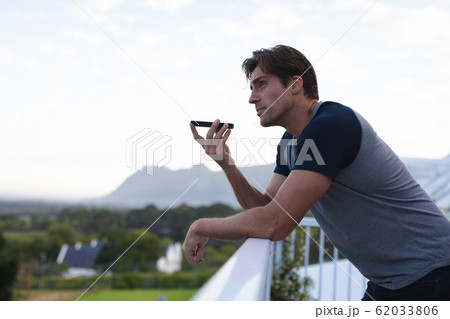 Young man talking on his mobile phone on terrace 62033806
