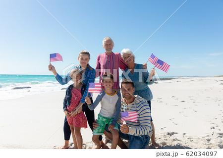 Family with american flag at the beach Family with american flag at the beach 62034097