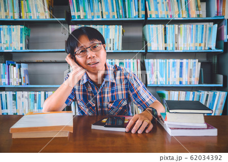 Bored asian student with books in library 62034392