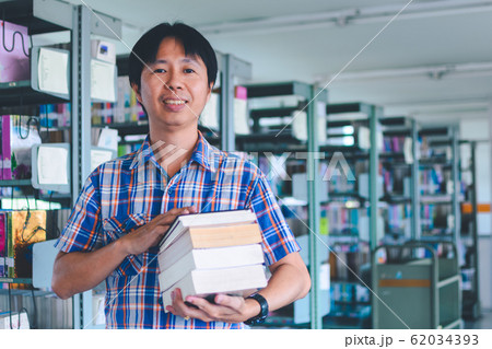 asian man student hold books in a library 62034393