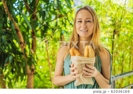Reusable grocery bags with bread in the hands of a young woman. Zero waste shopping. Zero waste 62036169