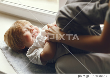 Mother and little son sitting on a windowsill Mother and little son sitting on a windowsill 62038657