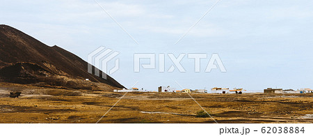 Village near Calhau crater on Sao Vicente Island, Cape Verde. Martian like surreal dry red ground surface of volcano Village near Calhau crater on Sao Vicente Island, Cape Verde. Martian like surreal dry red ground surface of volcano 62038884