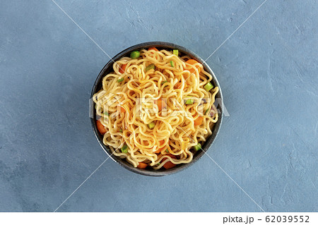 Instant noodles with carrot, scallions, and a sauce, a vegetable soba bowl, shot from above on a slate background Instant noodles with carrot, scallions, and a sauce, a vegetable soba bowl, shot from above on a slate background 62039552