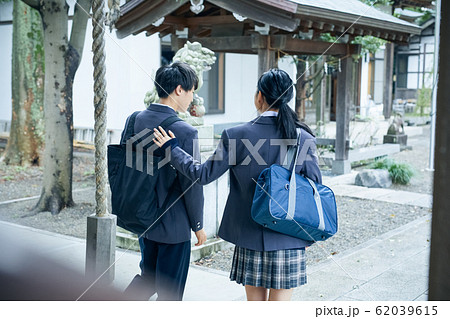 神社でお参りする高校生カップルの写真素材