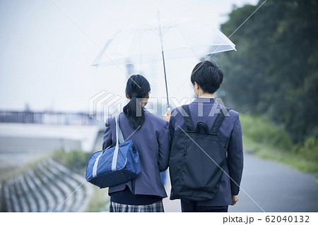 雨の日の高校生カップルの登下校の写真素材