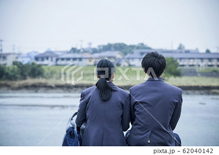 河原に座る高校生カップルの写真素材