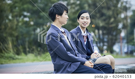 河原に座る高校生カップルの写真素材