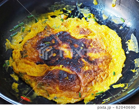 Overcooked omelette in flying pan. 62040690