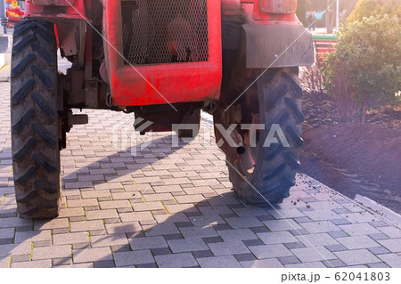 Tractor on the sidewalk in the city, gas from the exhaust pipe. Tractor on the sidewalk in the city, gas from the exhaust pipe. 62041803